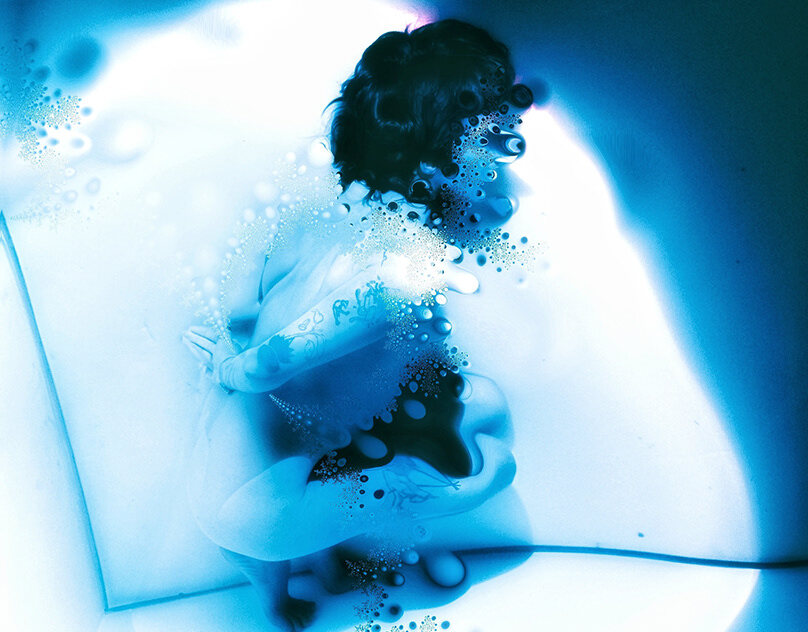Blue ink dispersing through pale water — an abstract study.