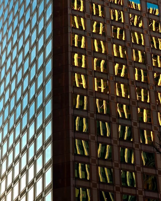 An urban building facade with windows lit warm at dusk.
